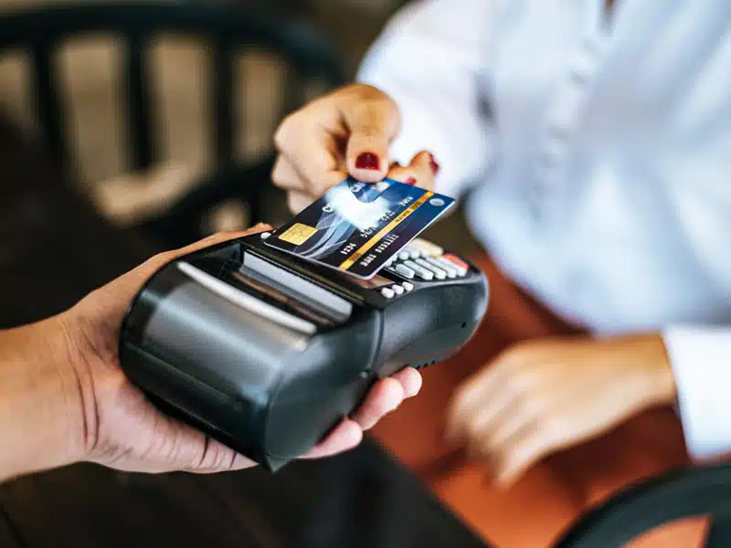 close up image of woman paying with credit card in cafe